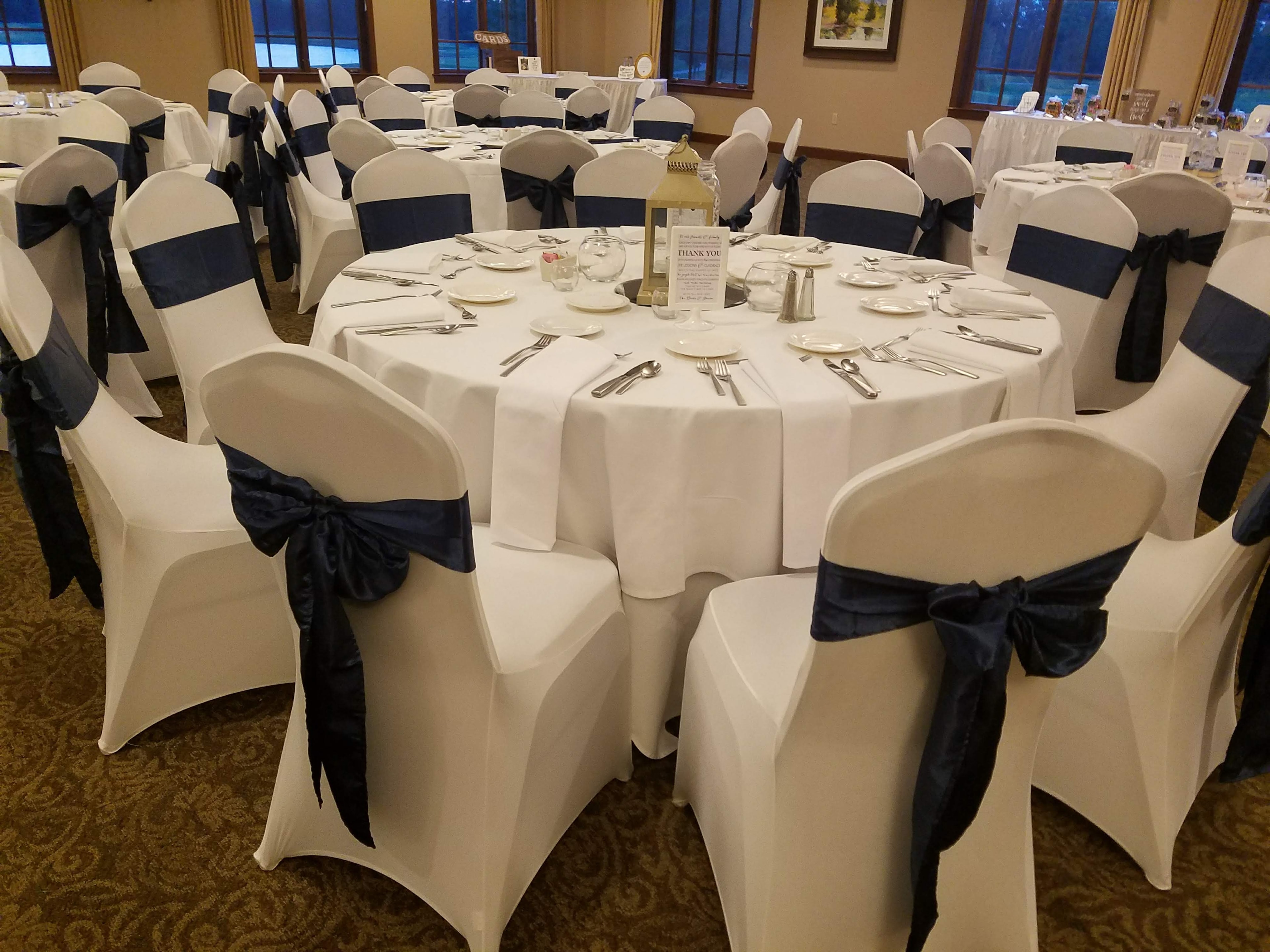 Close-up of white linens with navy satin bow detail
